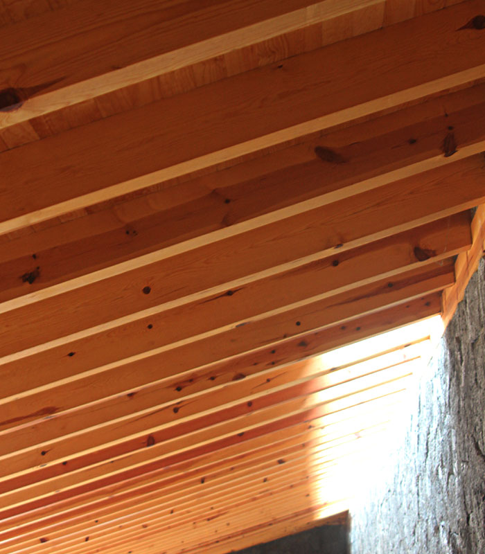 Estructura de madera con tragaluz y muro de piedra